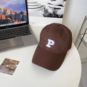 Detail of deep brown cotton baseball cap with white 3D embroidered P on a desk