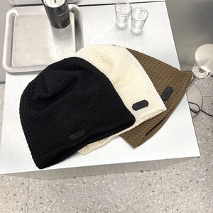 Tre colori di berretti in maglia a nido d ape nero beige e marrone con etichetta