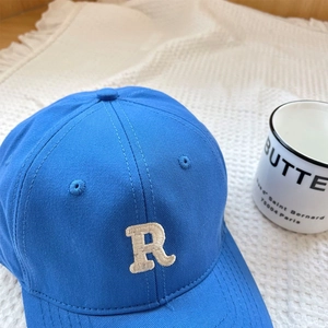 Detail of blue baseball cap with white R embroidery on a soft waffle fabric background