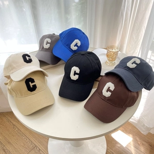 Classic baseball caps with C letter embroidery in multiple colors on a white table