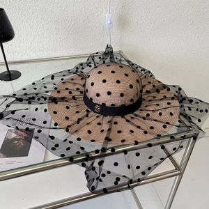 Détail du chapeau de paille à large bord avec tulle à pois et emblème M doré