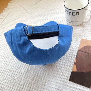 Detail of adjustable metal buckle on blue cotton baseball cap over white textured backdrop