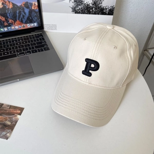 Detail shot of beige cotton baseball cap with embroidered letter P on white desk