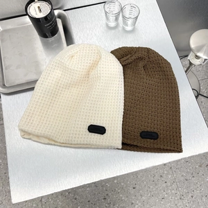 Dettagli di berretti in maglia a nido d'ape beige e marrone con patch logo