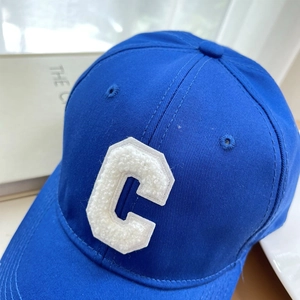 Detailed macro view of white chenille C patch on blue cotton twill baseball cap