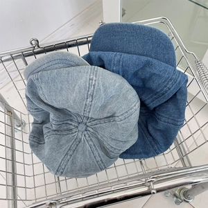 Oversized denim octagonal beret hats in light and dark blue washes in a metal basket