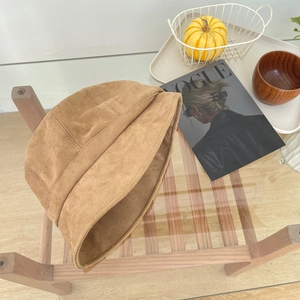 Detailopname van een suède vissershoedje op een rustieke houten tafel setting
