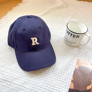 Detailed close-up of the 3D embroidered white R logo on a navy blue cotton baseball cap