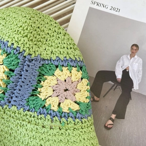 Detail van de handgehaakte groene strohoed met kleurrijke bloemen granny square patronen