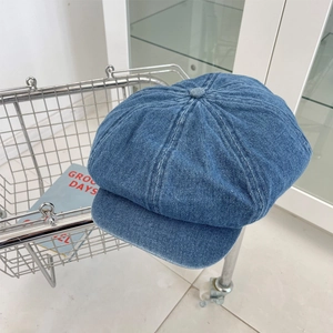 Detail of washed blue denim newsboy cap with multi-panel stitching and button top