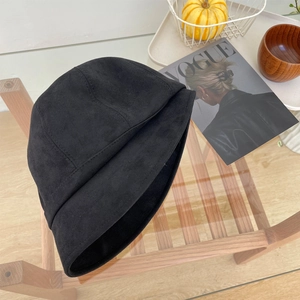 Detail van een zwarte vissershoed van imitatiesuède op houten tafel met een tijdschrift