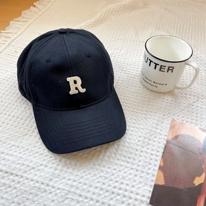 Close-up of white R letter embroidery and stitching on black cotton baseball cap