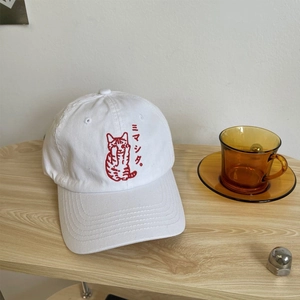 Detailed close-up of cute red cat embroidery on a white cotton baseball cap