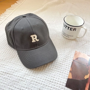 Close-up of a charcoal grey baseball cap featuring white R towel embroidery on soft cotton