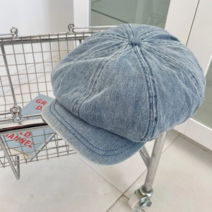 Detail of light blue denim newsboy cap with classic eight-panel stitching and metal basket