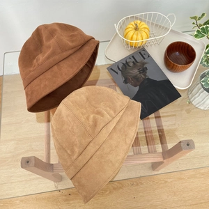 Vintage suède vissershoeden in karamel en kaki getoond op een glazen tafel
