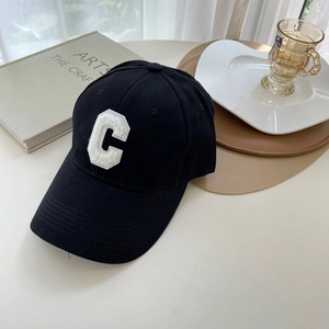 Detailed close-up of a black cotton baseball cap with white textured letter C patch