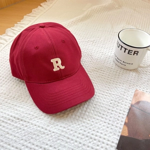 Detailed close-up of dark red baseball cap with white 3D embroidered R on waffle texture