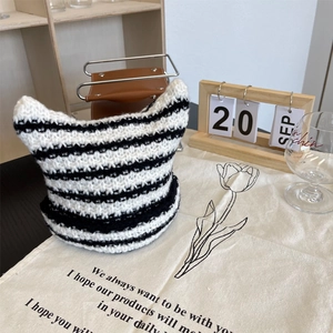 Detail of cute black and white striped cat ear knit beanie on a decorative cloth