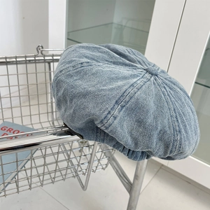 Detailed close-up of light blue denim newsboy cap hanging on a silver metal basket