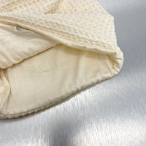 Dettaglio macro del tessuto a maglia waffle color crema con morbida fodera interna