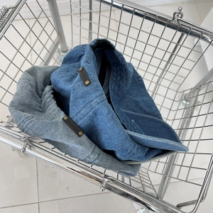 Detail of denim beret hats in blue shades with leather logo tags in a metal basket