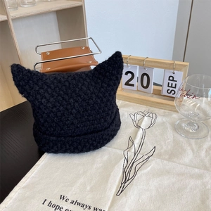 Close-up of thick black chunky knit cat ear beanie with textured pattern and pointed tips