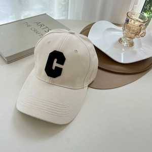 Close-up of beige cotton baseball cap featuring black chenille embroidery letter C detail