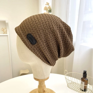 Dettaglio del berretto in maglia marrone con trama e etichetta in pelle fatta a mano