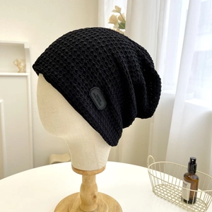 Dettaglio del berretto nero in maglia a nido d'ape con etichetta in pelle stile artigianale