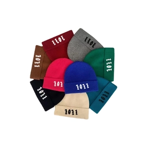 Flat lay di berretti in maglia colorati con ricamo di numeri su fondo bianco