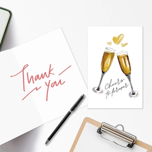 Detailed view of Cheers to forever champagne wedding cards and Thank You note on clipboard