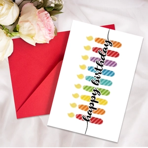 Set biglietti compleanno con candele arcobaleno e busta rossa su sfondo di seta
