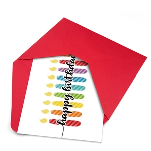 Dettaglio di un biglietto di compleanno bianco con candele arcobaleno e busta rossa