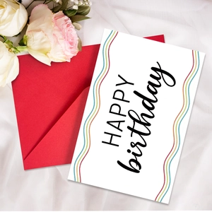 Dettaglio del biglietto di compleanno con onde colorate e busta rossa su tessuto di seta