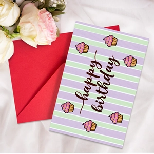 Dettaglio del biglietto d'auguri con cupcake e busta rossa su tessuto di seta pura