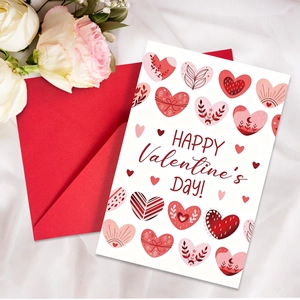 Detalle de tarjeta de San Valentín con sobre rojo y corazones rosas sobre tela