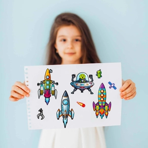 Fille tenant des autocollants d'espace avec fusées et ovnis pour puzzles créatifs