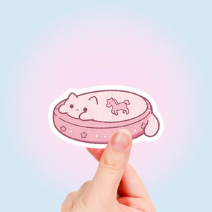 Close-up of a cute pink cat sticker held by hand to show the decorative laptop decal size