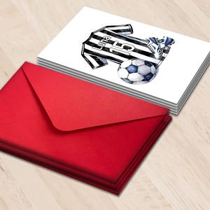 Set di biglietti d'auguri calcio con buste rosse e maglia ad acquerello su tavolo in legno