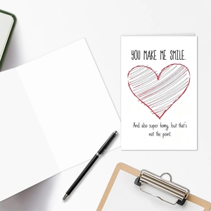 Close-up of minimalist Valentine card with red heart on a wooden clipboard with pen