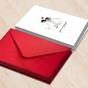 Close-up of penguin theme greeting cards with red envelopes on a wooden desk