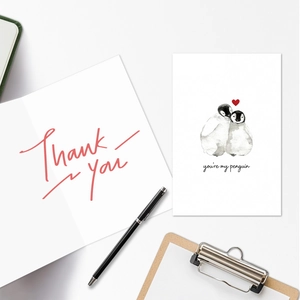 Detailed view of watercolor penguin card and 'Thank You' text with modern office stationery