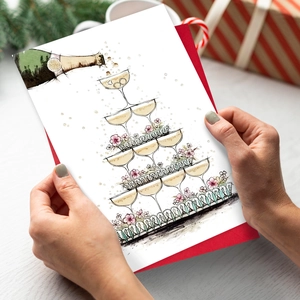Close-up of hands holding a wedding greeting card with champagne tower illustration