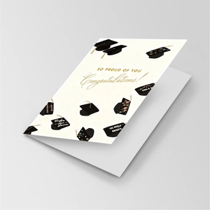 Detailed view of graduation card with black mortarboard patterns and gold tassels