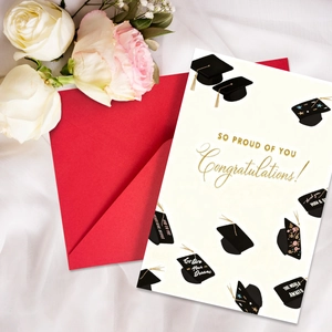 Detail of graduation greeting card with gold lettering and red envelope on silk