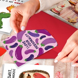 Close-up of hand placing a funny eggplant love greeting card into a red envelope