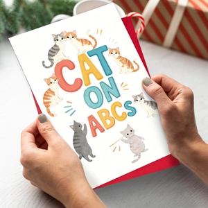 Cartoon cat greeting card set with red envelope held in hands for holiday gifting