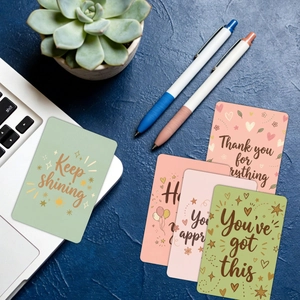 Flat lay of motivational cards with Keep Shining text on a desk with a laptop