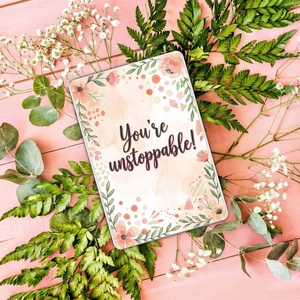 Detailed view of floral watercolor card with You're unstoppable text on pink wood
